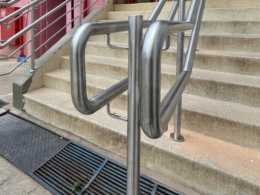 Corrimão de inox em rampa e escadaria de acesso com piso tátil