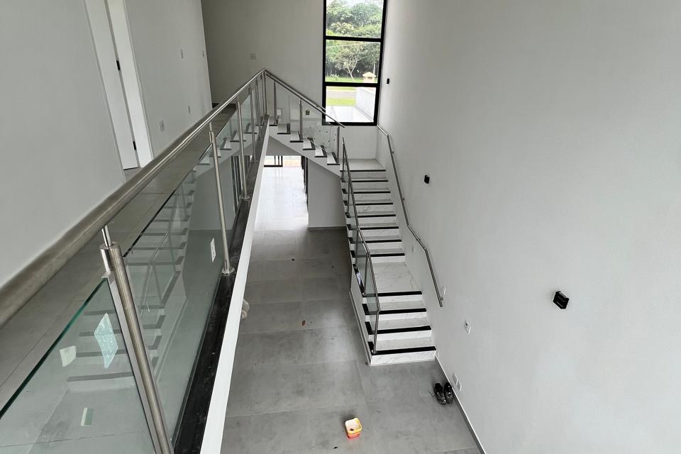 Vista superior do vão com mezanino de vidro e escada com corrimão de inox — Cond. Campos de Conde