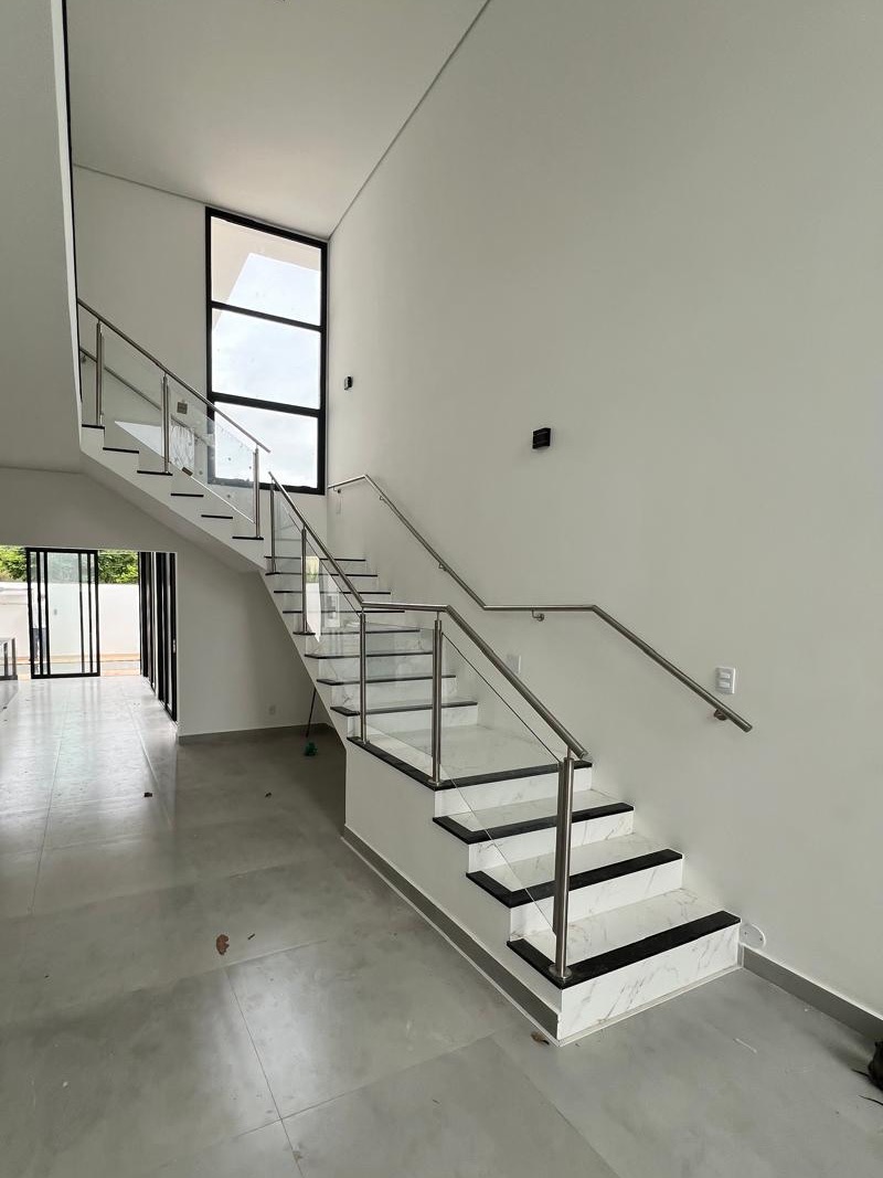 Sala de pé-direito duplo com escada e corrimãos de inox — Cond. Campos de Conde