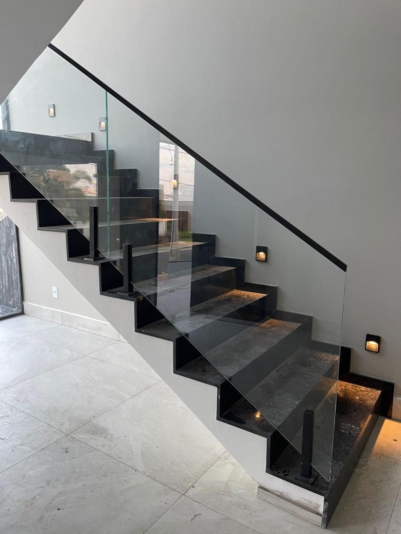 Escada de granito preto com guarda-corpo de vidro e iluminação embutida no condomínio Ecovilla, em Valinhos