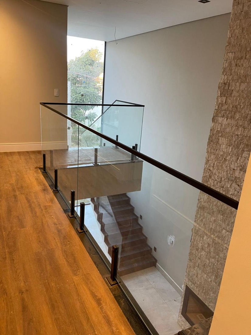 Mezanino com piso de madeira, guarda-corpo de vidro e corrimão — Ecovilla