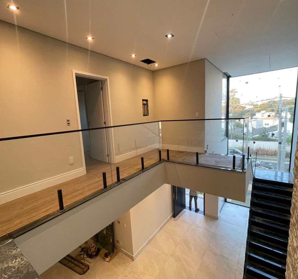 Hall de pé-direito duplo com parede de pedra e guarda-corpo de vidro — Ecovilla, Valinhos